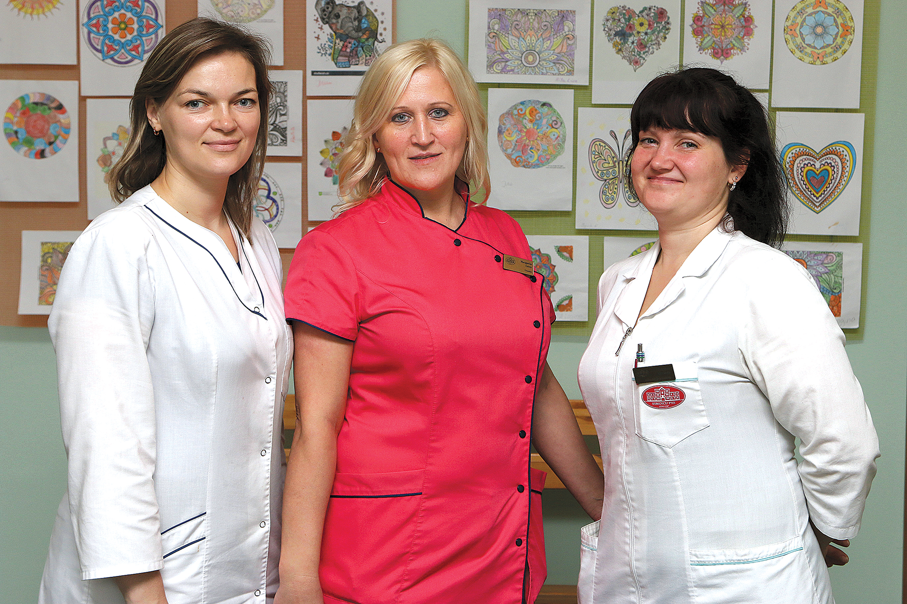 Kopā ar kolēģēm.  No kreisās ergoterapeite  Zane Golovanova,  Margarita Grīva,  saimniecības vadītāja  Kristīne Moiseja.  Fonā pacientu  krāsotas mandalas