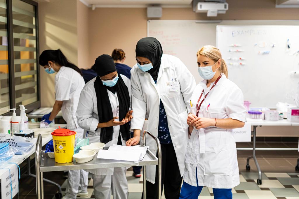 Raksta autore Anna Paškova ar medicīnas studentiem praktiskās nodarbības laikā RSU Mācību izglītības tehnoloģiju centra mācību telpās. Attēlā redzamā daudzveidība atgādina, cik būtiska ir starpkultūru komunikācija veselības aprūpes izglītībā un praksē